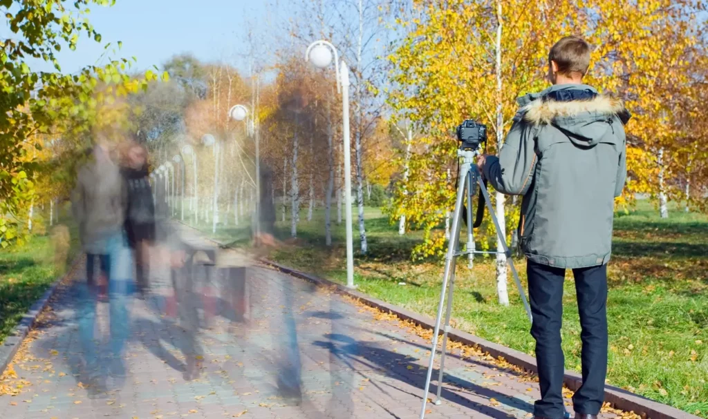 Photographer takes a time lapse photo in a fall park.