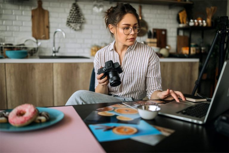 Girl holding camera looking at her computer