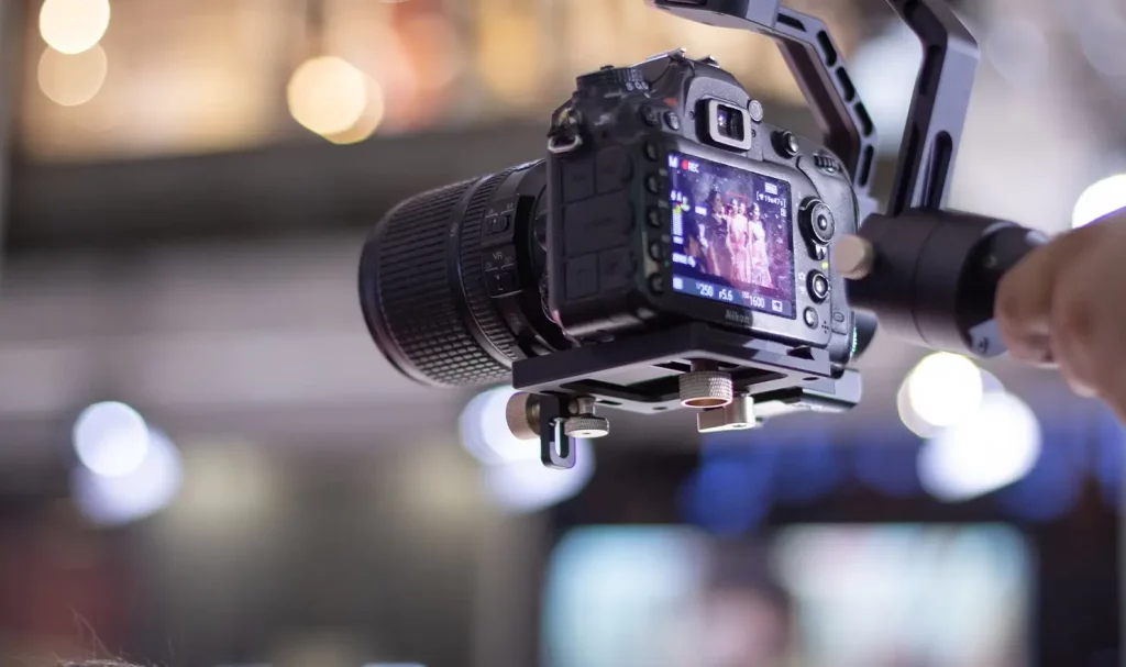 Close up of a video camera on a handheld gimbal with a blurred background.