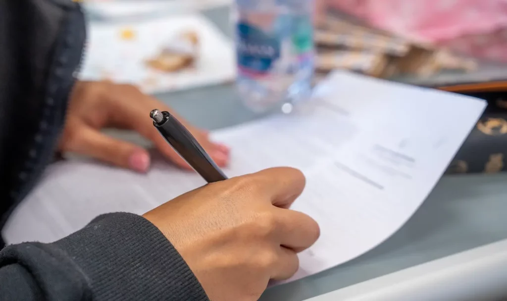 Close-up of a model's hands while signing a model release form with a black click-top pen.